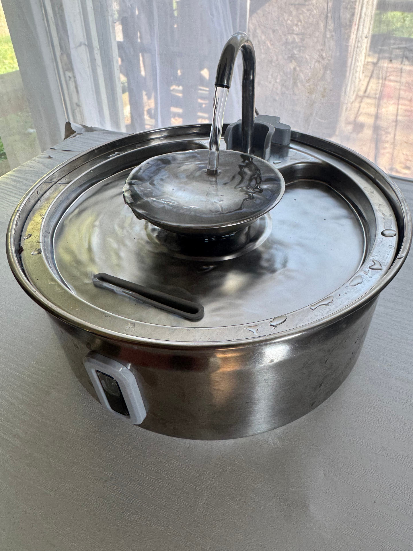 Side view of the Dripurr stainless steel cat water fountain with the swan-neck spout flowing into the central bowl