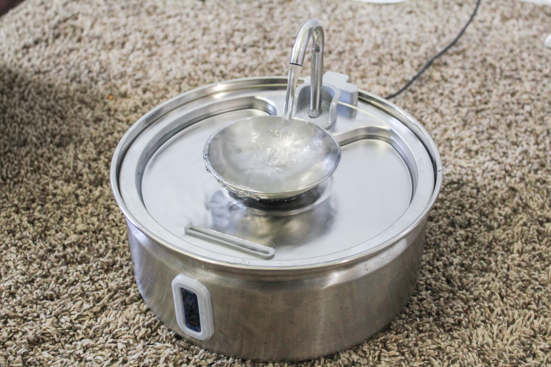 Dripurr stainless steel fountain running on carpet with water cascading into the central bowl